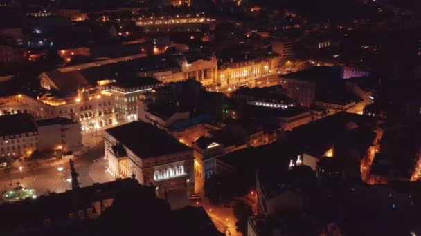 Pomalu vpřed letící drone kamera nad nočním městem. Kamera se nakloní dolů na Restauradores náměstí s obelisk uprostřed. Letecký pohled na historickou budovu divadla Eden. Lisabon, hlavní město Portugalska. — Stock video