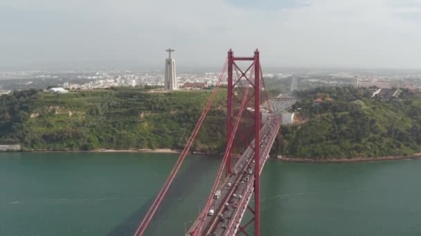 Luftaufnahme der großen roten Schrägseilbrücke vom 25. April über den Tejo. Mehrspurige Straße mit starkem Verkehr durch Drohnen. Jesusstatue auf hohem Sockel. Lissabon, Hauptstadt von Portugal. — Stockvideo