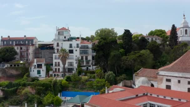 Drohnen-Kamera verfolgt Geländeprofil und steigt über Hügel. Über Häuser zum alten Sankt-Georgs-Schloss fliegen. Offenbarendes Stadtpanorama. Lissabon, Hauptstadt von Portugal. — Stockvideo