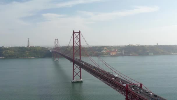 Emelt kilátás a hosszú piros kábeles hídra a Tagus folyó felett. Többsávos út nagy forgalommal a dróntól. Lisszabon, Portugália fővárosa. — Stock videók