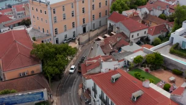 Vista aérea do eléctrico que conduz nas ruas da cidade. Câmera Drone inclina-se para o panorama da cidade com longa ponte sobre o rio. Lisboa, capital de Portugal. — Vídeo de Stock