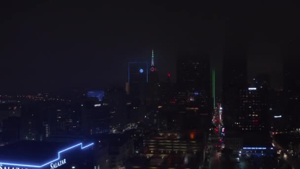 Drone in volo verso Mercantile National Bank Building con torre e grande orologio al neon. Vista aerea notturna del centro. Dallas, Texas, Stati Uniti — Video Stock