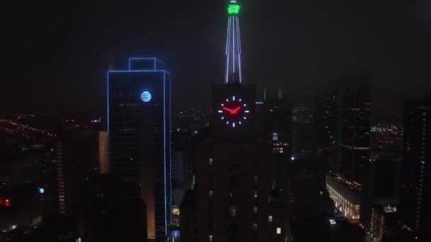 Kleurrijke Neon verlichte spike en klok op de top van Mercantile National Bank Building. Luchtdrone nacht, uitzoomen van beelden. Dallas, Texas, Verenigde Staten — Stockvideo