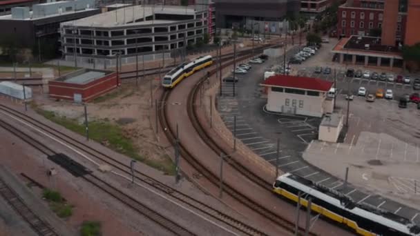 Letecký pohled na dva vlaky s více elektrickými jednotkami projíždějící jeden kolem druhého. Metropolitní cestující DART Light Rail. Dron letí dopředu a naklání se dolů. Dallas, Texas, USA — Stock video