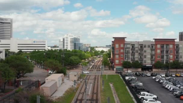 Vue aérienne de la ligne de chemin de fer à double voie vide qui traverse la ville. Voitures circulant au passage à niveau. Un drone volant en avant. Dallas, Texas, USA — Video