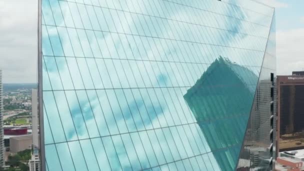 Niebo i otaczające je drapacze chmur odbijające się w pochyłej szklanej fasadzie wysokiego budynku. Widok z lotu drona latającego wokół fontanny. Dallas, Teksas, USA — Wideo stockowe