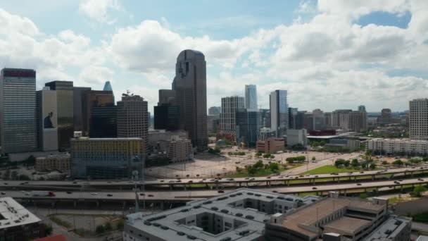 Πανοραμική εναέρια θέα των ουρανοξυστών του κέντρου πίσω από την εθνική οδό. Ψηλό σύγχρονο κτίριο γραφείων panning πλάνα από drone. Ντάλας, Τέξας, ΗΠΑ — Αρχείο Βίντεο