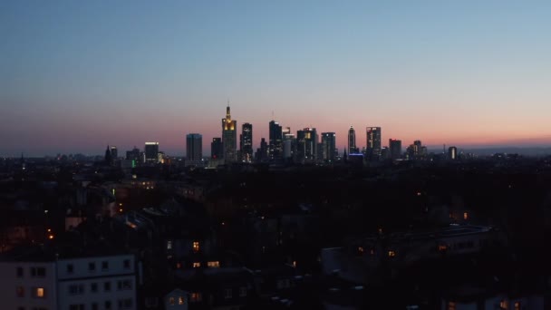 Fotografering av drönare från en låg flygning ovanför kvällsstaden. Spårningsvy över skyline mot färgglad himmel. Frankfurt am Main, Tyskland — Stockvideo