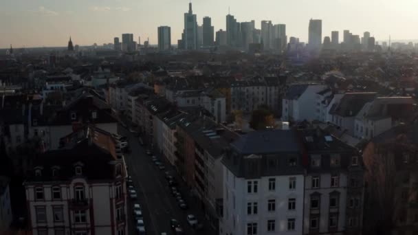Voorwaarts bewegende en stijgende drone Luchtfoto van de buurt en wolkenkrabbers in de verte. De skyline tegen de zon. Frankfurt am Main, Duitsland — Stockvideo