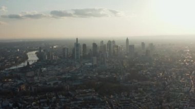 Şehir merkezindeki yüksek modern binaların havadan görüntüsü. Yavaşça geriye doğru uçan drone 'lardan. Gökdelenleri parlak gökyüzüne karşı olan bir şehir. Frankfurt am Main, Almanya