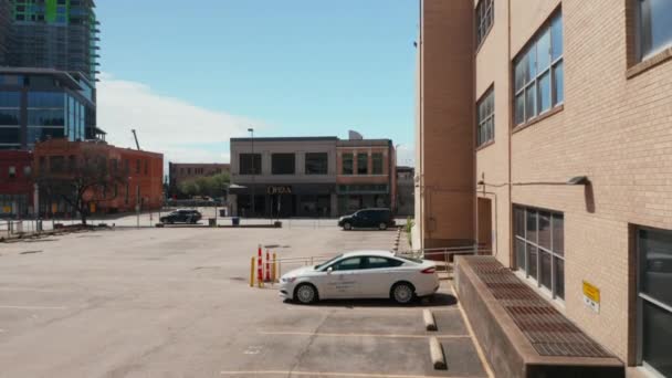 Fotografier av ensam vit personbil vistas på parkeringen i stan från drönare mjukt landar på asfalt drönare. Dallas, Texas, USA — Stockvideo