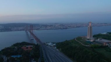 Lizbon sahili geniş panoramik manzaralı şehir merkezi, Santuario de Cristo Rei anıtı ve kırmızı Ponte 25 de Abril köprüsü boyunca araba trafiği