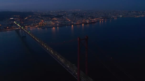 Panorama aéreo noturno do centro urbano de Lisboa em luzes com Ponte 25 de Abril ponte vermelha a atravessar o mar — Vídeo de Stock