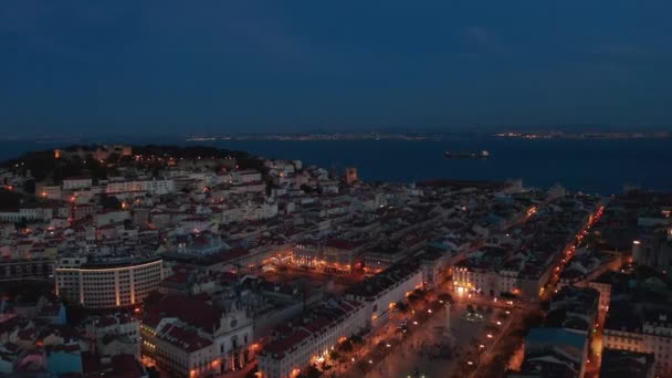 Letecká noc pohled na centrum města Lisabonu s řadami tradičních moderních domů, hrad na kopci a velké veřejné náměstí se světly — Stock video