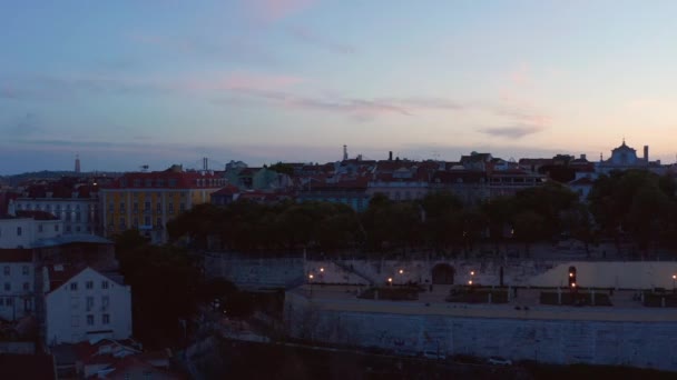 Letecký posuvník pohled na tradiční malé domy v centru města Lisabonu s odhalením Ponte 25 de Abril červený most přes moře v pozadí — Stock video