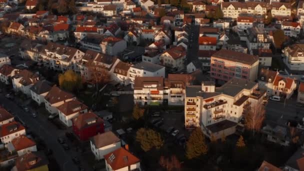 Drone volant en avant au-dessus des rues avec des maisons familiales dans le quartier urbain. Façades de la Maison Blanche éclairées par le soleil du soir. Vue aérienne. Bad Vilbel, Allemagne. — Video