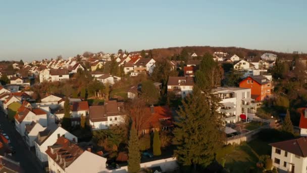 Drone volando sobre casas familiares iluminadas por el sol brillante de la tarde. Vista aérea en zona residencial. Bad Vilbel, Alemania. — Vídeo de stock