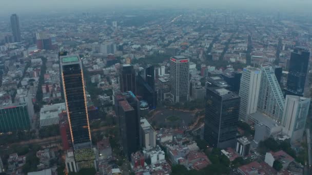 Luchtfoto nadert op grote rotonde kruising met drukke verkeer omgeven door hoge moderne wolkenkrabbers in Mexico City — Stockvideo