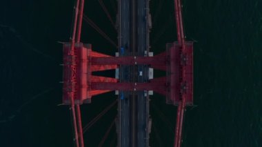 Kuşlar yukarıdan aşağıya, asma köprüdeki çok şeritli yolda koyu arkaplana doğru giden arabaları görüyorlar. Soyut görüntüyü geri çek. Ayna etkisi. Lizbon, Portekiz.