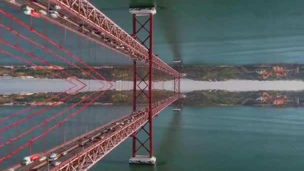 Abstract hyperlapse shot of fly through big red suspension bridge over wide river. Computer added horizontal mirror effect. Lisbon, Portugal. — Stock Video