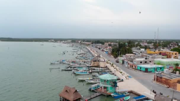 Adelante revelan barcos amarrados a lo largo del paseo marítimo. Bajo vuelo por encima del puerto en la pequeña ciudad costera. Rio Lagartos, México. — Vídeo de stock