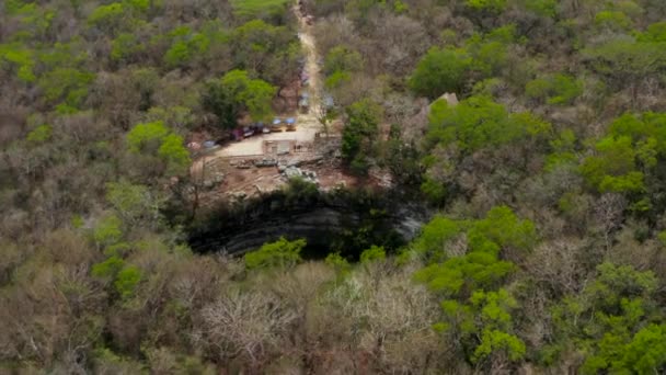 İleri doğru eğilme, yerdeki Cenote obruğunun büyük yuvarlak şeklini ortaya çıkarıyor. Güneş su yüzeyine yansıyor. Kolomb öncesi dönemin tarihi anıtları, Chichen Itza, Meksika. — Stok video