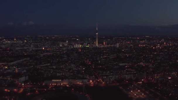 Voo sobre a cidade grande à noite. Vista aérea do bairro urbano e cidade dominante, torre de TV fina alta Fernsehturm. Berlim, Alemanha. — Vídeo de Stock