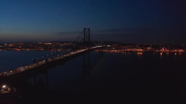 Vista aérea da Ponte 25 de Abril ponte vermelha com trânsito automóvel e centro da cidade de Lisboa com luzes ao fundo — Vídeo de Stock