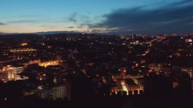 Şehir merkezindeki modern binalarla çevrili büyük halk meydanına doğru gece Lizbon şatosunun üzerinde uçuyorlar.