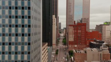 Gökdelenler arasında caddenin üzerinde ilerliyorlar. Yansıyan cam cepheleriyle binaya doğru gidiyor. Dallas, Teksas, ABD.