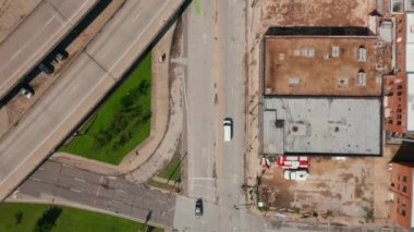 Havadan kuşların gözü yukarıdan aşağıya beyaz minibüsün görüntüsünü takip ediyor. Otoyol kavşağının altındaki caddelerden geçen bir araba. Dallas, Teksas, ABD.