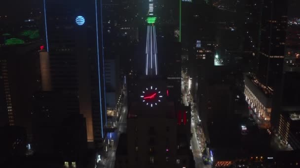 Nach hinten zeigen und kippen neonbeleuchtete Spitze und Uhr auf dem Gebäude der Mercantile National Bank. Nachtansicht per Drohne. Dallas, Texas, USA. — Stockvideo