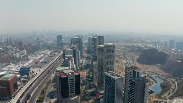 Hochwinkelblick auf eine Gruppe hoher Wolkenkratzer im modernen Stadtteil Santa Fe, der sich zwischen mehrspuriger Straße und öffentlichem Park befindet. Mexiko-Stadt. — Stockvideo