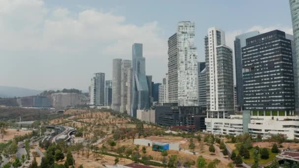 Grabación de aterrizaje en parque público junto a rascacielos modernos en el distrito de Santa Fe. Vista de ángulo bajo de edificios altos. Ciudad de México, México. — Vídeos de Stock