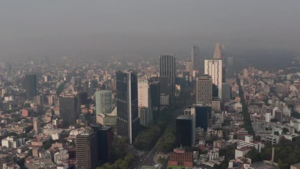 Förhöjd panorering utsikt över hög kontorsbyggnad i centrum. Begränsad sikt på grund av luftföroreningar. De kretsar runt skyskrapor. Mexico City, Mexiko. — Stockvideo