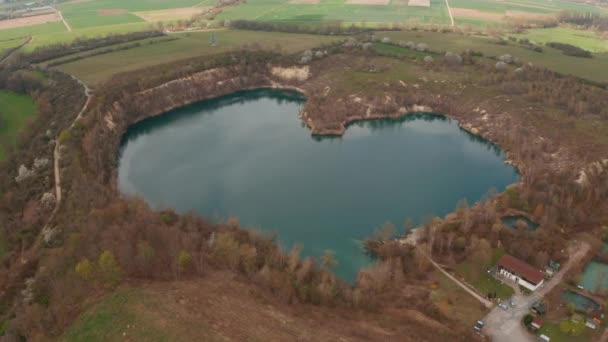 Para trás revelam arredores de lago em forma de coração natural no campo. Vista aérea da paisagem rural. Alemanha. — Vídeo de Stock