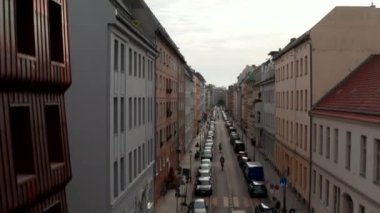 Yükselen görüntüler şehir manzarasını gösteriyor. Çevredeki panoramik manzaraya göre park etmiş arabalarla bisiklet güzergahı caddesinde çekilmiş. Berlin, Almanya.