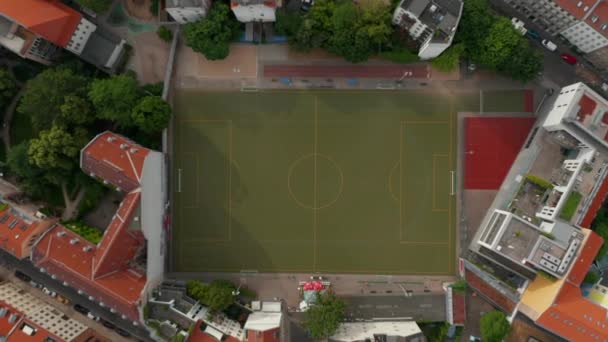 Volatili aerei occhio sopra vista dall'alto verso il basso dal drone ascendente. Rocket shot di campo da calcio strettamente circondato da edifici. Berlino, Germania. — Video Stock