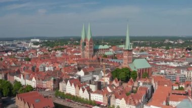 İleri, ortaçağ şehir merkezindeki tarihi tuğla binalara doğru uçuyor. Kuzey Alman gotik kiliseleri. Luebeck, Schleswig-Holstein, Almanya