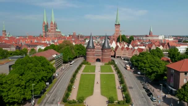 Inclinado hacia adelante revelan el centro histórico de la ciudad. Casas de ladrillo rojo, iglesias y edificios. Vuela entre torres de la Puerta de Holsten. Luebeck, Schleswig-Holstein, Alemania — Vídeo de stock