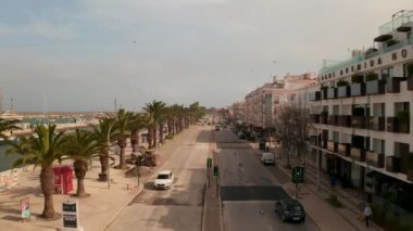 Portekiz 'de Sagres, Lagos kıyısında yayalar üzerinde yürüyen insanların bulunduğu yüksek hızlı hava görüntüsü binalar ve diğer ucunda okyanus olan dükkanlar.