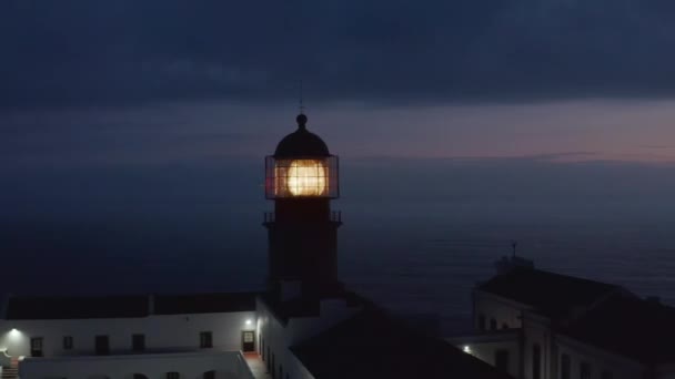 Skiner fyr strålkastare ljus i skymningen, drönare cirkla runt med bakgrund kväll havet, Lagos, Portugal — Stockvideo