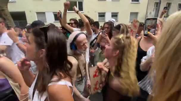 Активний літній чоловік з навушниками танцює з молодою жінкою на параді на вулиці Крістофер, відзначаючи свободу і гордість перед трансгендерністю і lgbt в Берліні, Німеччина. — стокове відео