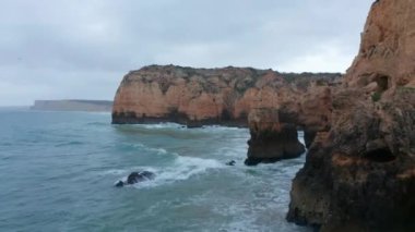 Atlantik Okyanusu üzerinde uçan hava aracı Lagos, Algarve, Portekiz 'deki manzaralı renkli kayalık kıyı şeridini gösteriyor.