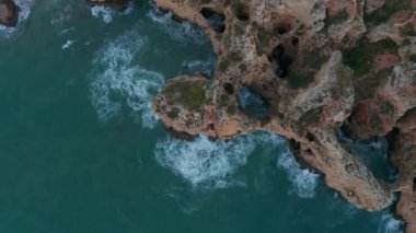 Lagos, Algarve, Portekiz 'deki gökyüzü kuşlarının yukarıdan aşağı bakan manzaralı Lagos renkli kayalık sahili.