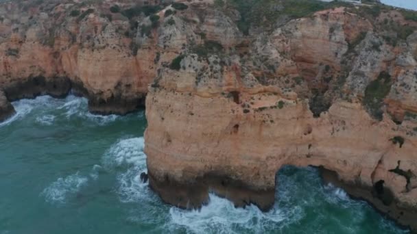 Aerial drone tilt down above rocky cliff coast in Lagos, Algarve, Portugal, birds eye overhead down, windy day — Vídeos de Stock