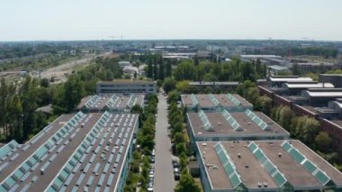 Endüstriyel alandaki binaların üzerinden iniyor. Tavan pencereleri ve fotovoltaik panelleri olan düz çatılar. Berlin, Almanya