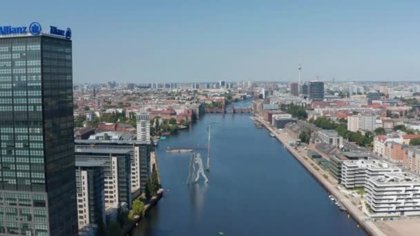 Hacia adelante desciende volar por encima del río Spree hacia Molecule Man escultura alta. Vista aérea de la ciudad. Día soleado con cielo despejado. Berlín, Alemania — Vídeo de stock