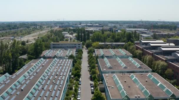 Endüstriyel alandaki binaların üzerinden iniyor. Tavan pencereleri ve fotovoltaik panelleri olan düz çatılar. Berlin, Almanya — Stok video