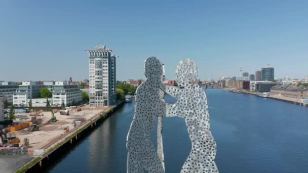 Revers révèlent la sculpture Molecule Man dans la rivière Spree et divers bâtiments entourant l'eau calme. Journée ensoleillée avec ciel dégagé. Berlin, Allemagne — Video